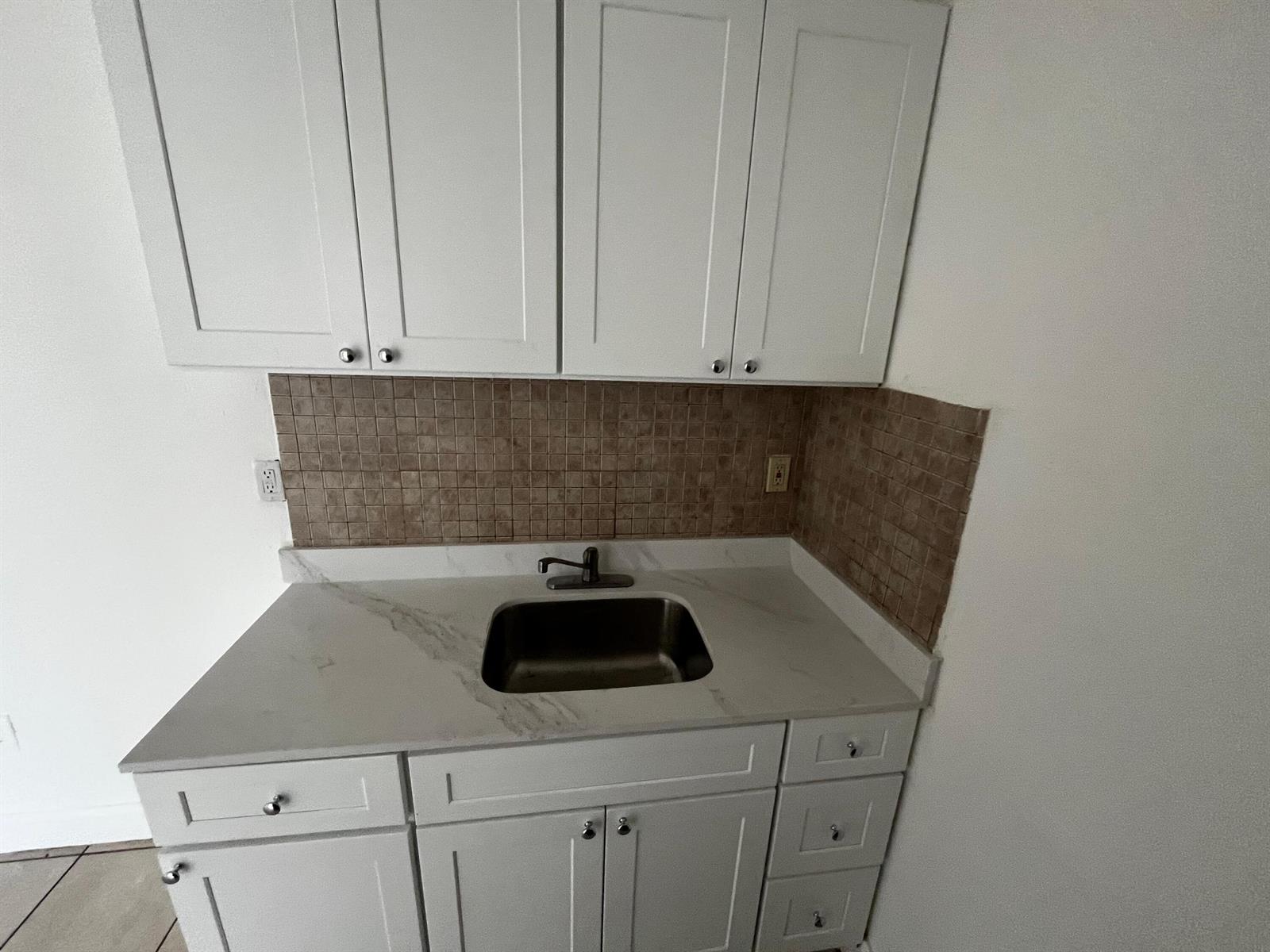 A kitchen area features white cabinets, a stainless steel sink, and a brown tiled backsplash — 3015 NW 8th Avenue # 11, Miami FL 33127, MIAMI, FL