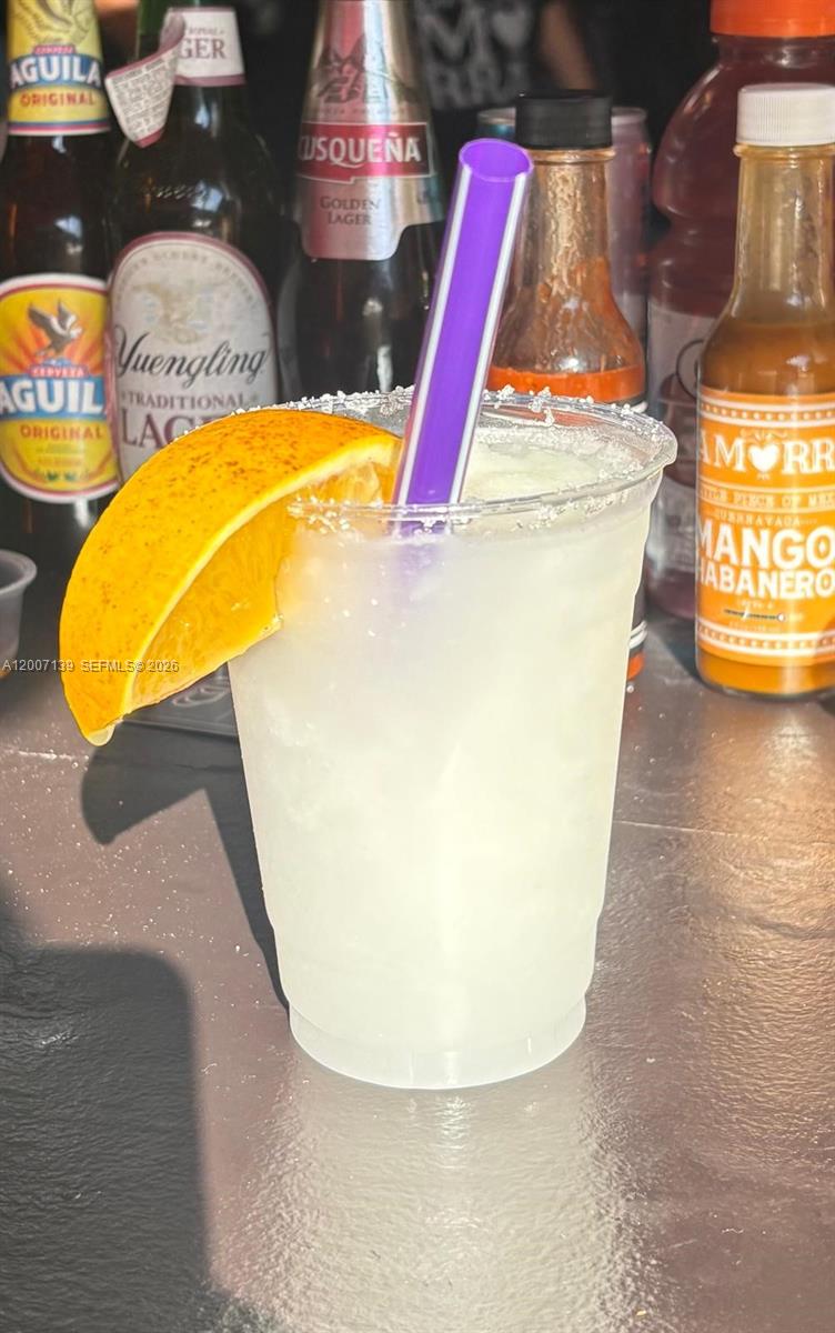 A plastic cup with a salted rim, orange slice, and purple straw sits on a counter — E Sheridan, Hollywood FL 33021, HOLLYWOOD, FL