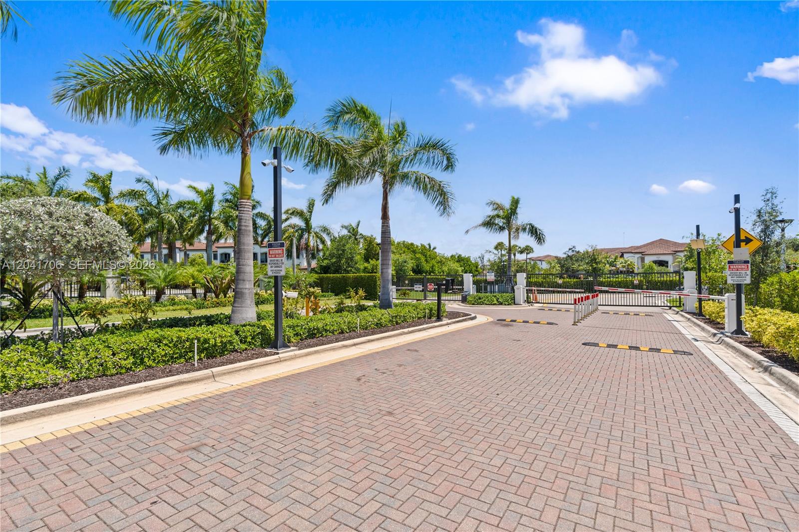 A paved driveway leads to a gated entrance surrounded by palm trees and landscaping — 21018 NE 8th Ave # 21018, Miami FL 33179, MIAMI, FL