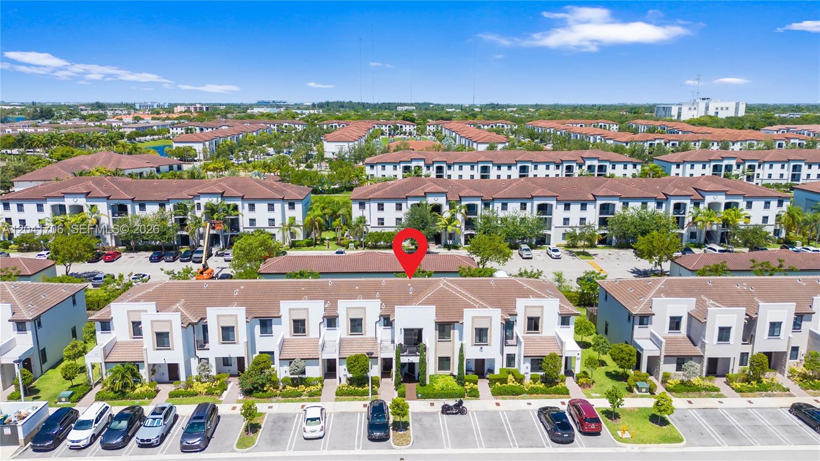 An aerial view shows a row of multi-story townhomes with tiled roofs and parking spaces — 21018 NE 8th Ave # 21018, Miami FL 33179, MIAMI, FL