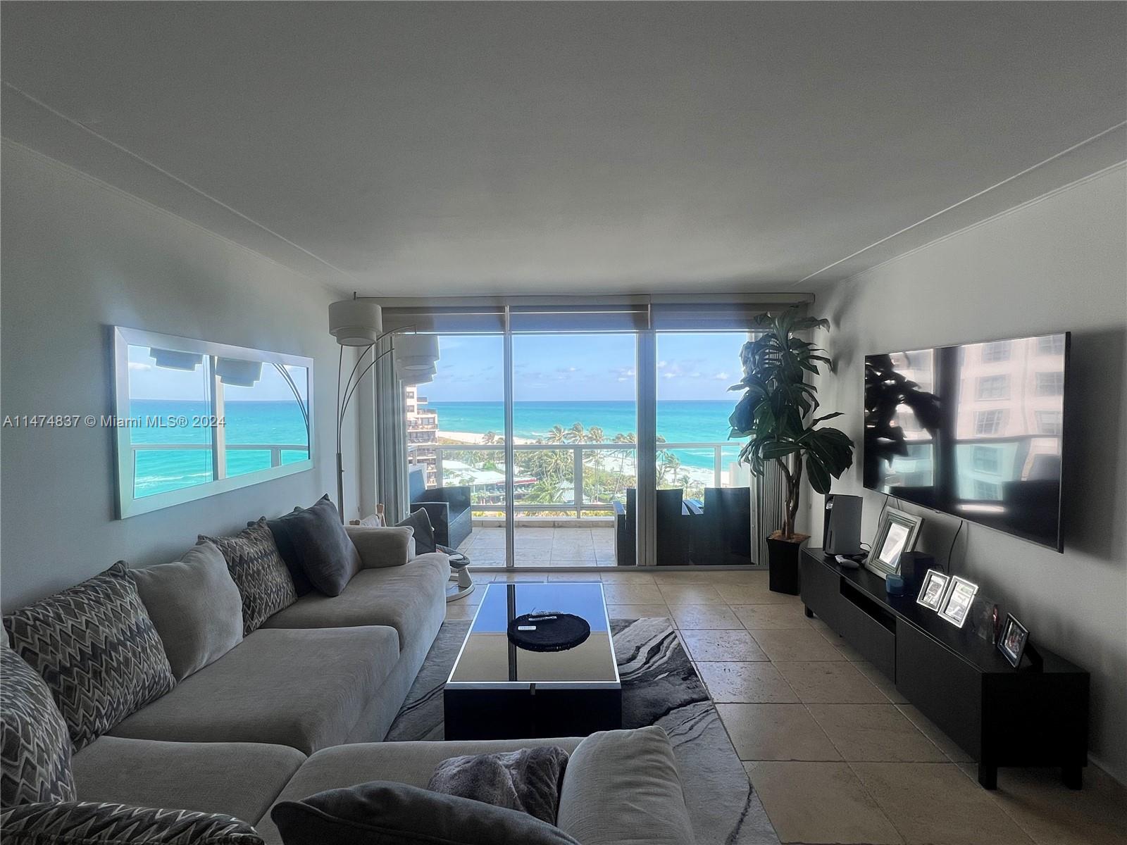 A living room features a sectional sofa, a glass coffee table, and a balcony view — 5151 Collins Ave # 1035, Miami Beach FL 33140, MIAMI BEACH, FL
