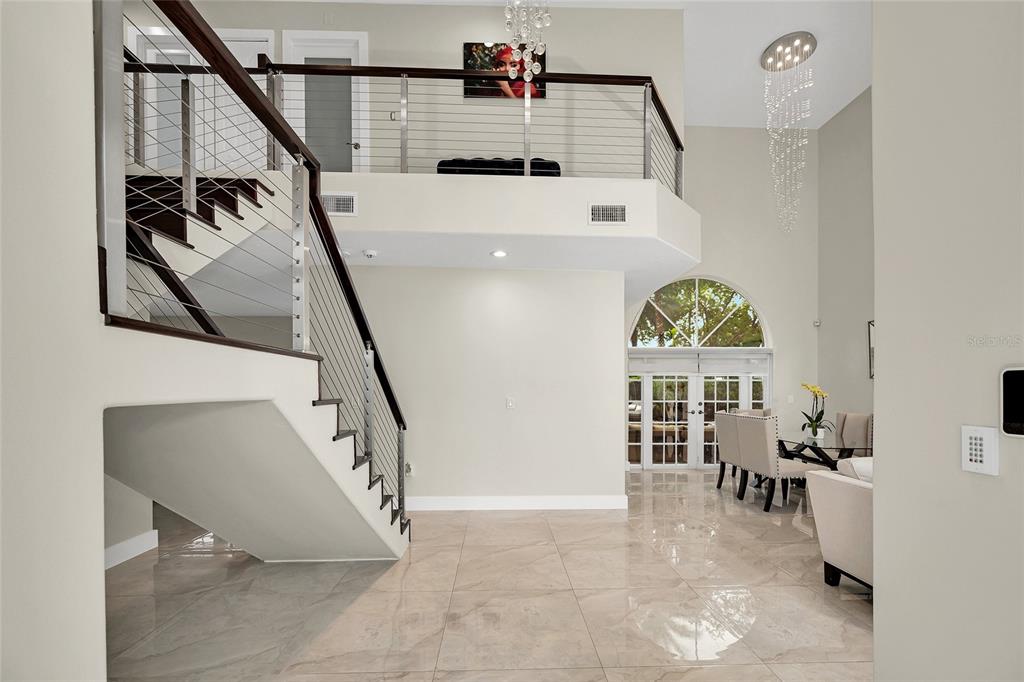 A modern foyer features a floating staircase, tile flooring, and a balcony overlooking the space — 1385 SW 143RD COURT, MIAMI, FL