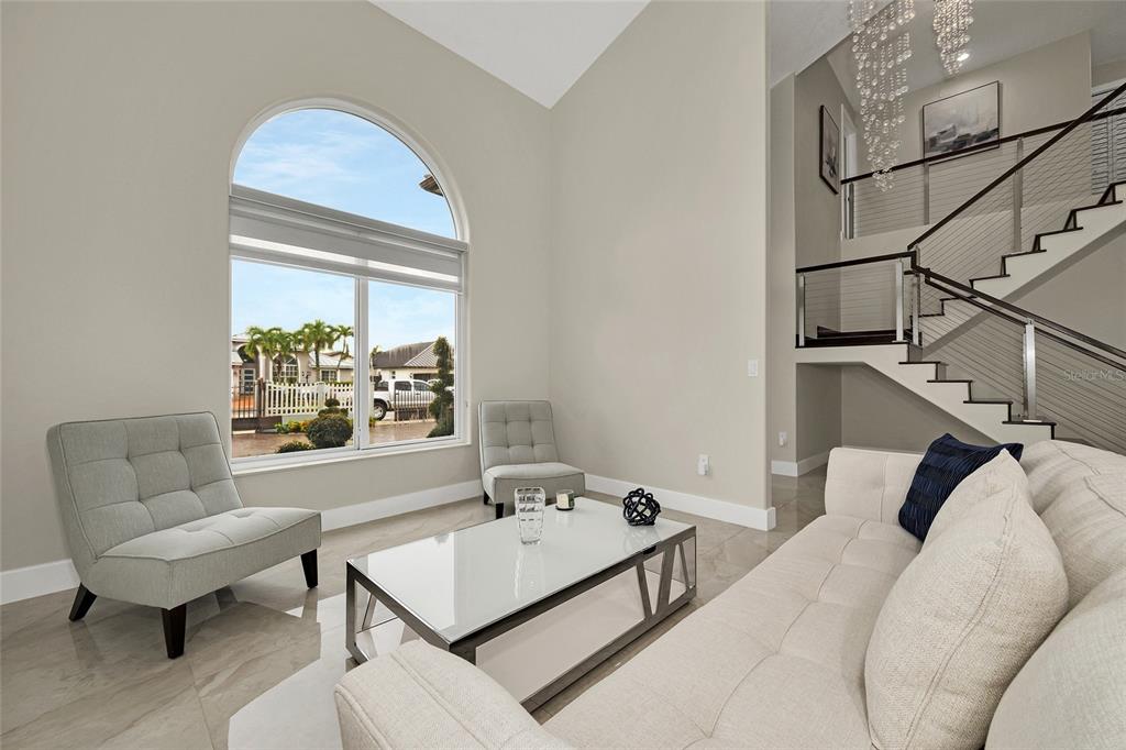 A living room features a vaulted ceiling, a large arched window, and a modern staircase — 1385 SW 143RD COURT, MIAMI, FL