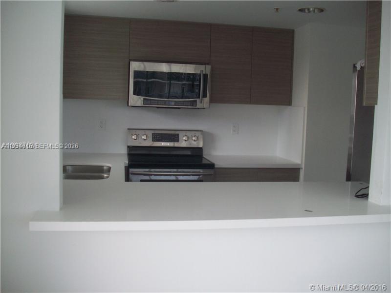 A kitchen with light wood cabinets, stainless steel appliances, and a white breakfast bar — 1402 Brickell Bay Dr # 1103, Miami FL 33131, MIAMI, FL