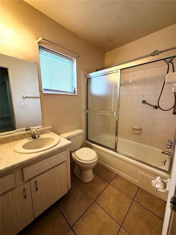 An empty dining room features beige tile flooring, a ceiling fan, and a white door — 5994 HIBISCUS DRIVE, BRADENTON, FL