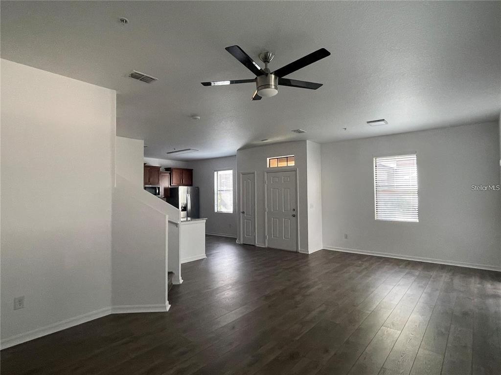 An open-concept living area features wood-look flooring, a ceiling fan, and an adjacent kitchen — 3723 SENECA CLUB LOOP UNIT 31-102, ORLANDO, FL