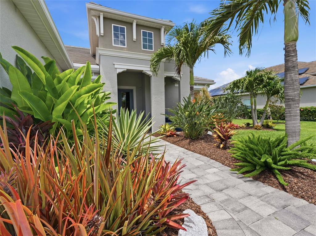 A paved walkway leads to the entrance of a house surrounded by tropical landscaping — 21253 CHATTAHOOCHEE AVENUE, VENICE, FL