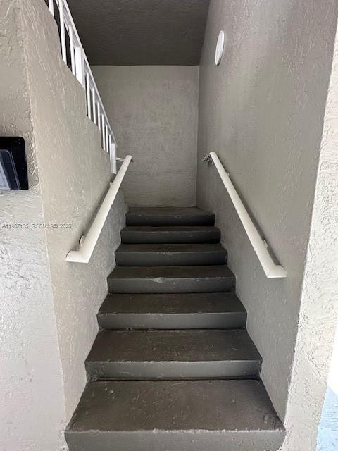 A set of concrete stairs with white handrails leads upward between two beige walls — 7510 SW 152nd Ave # C201, Miami FL 33193, MIAMI, FL