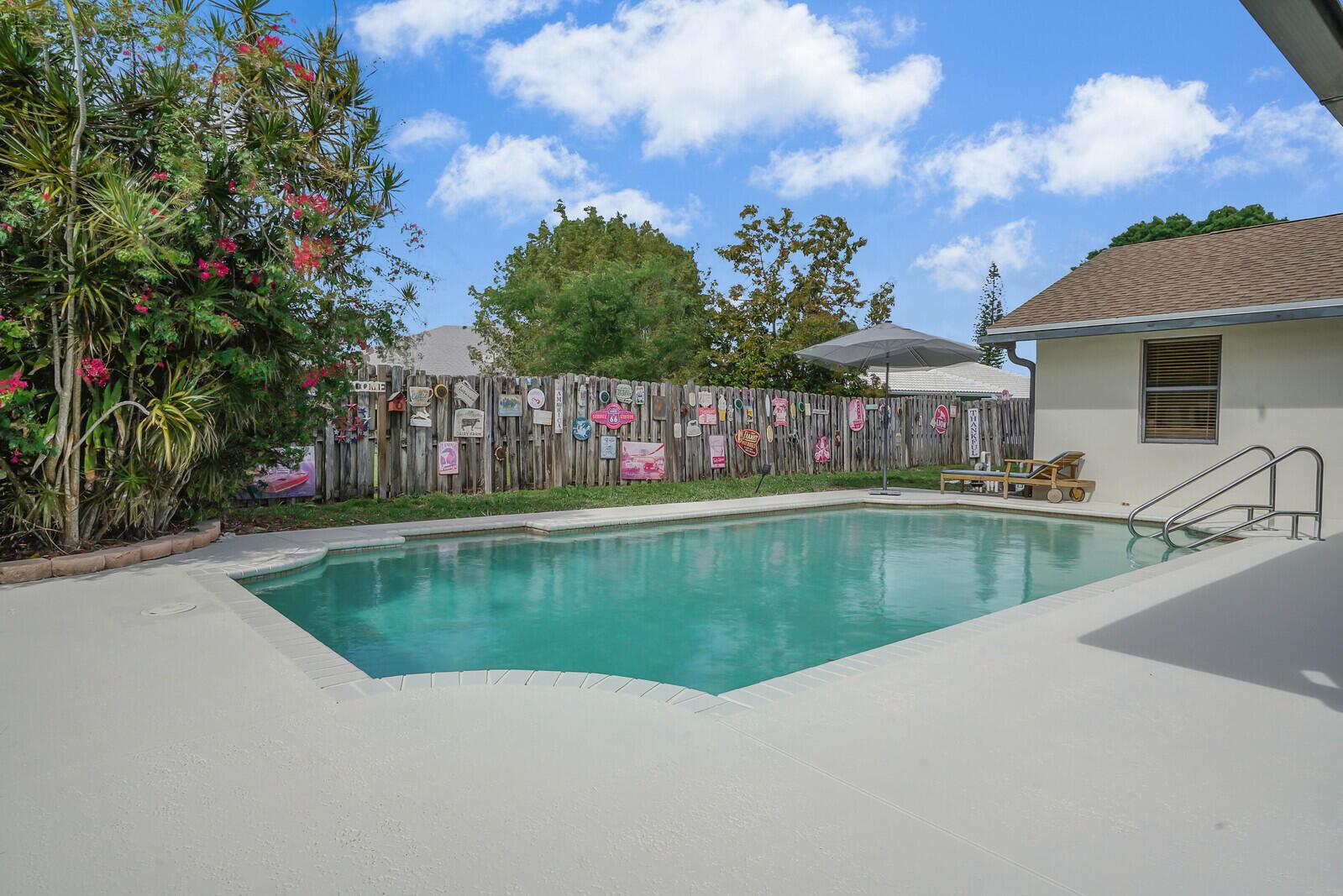 A backyard swimming pool with a patio, wooden fence, and a house exterior — 13834 Geranium Place, Wellington FL 33414, WELLINGTON, FL