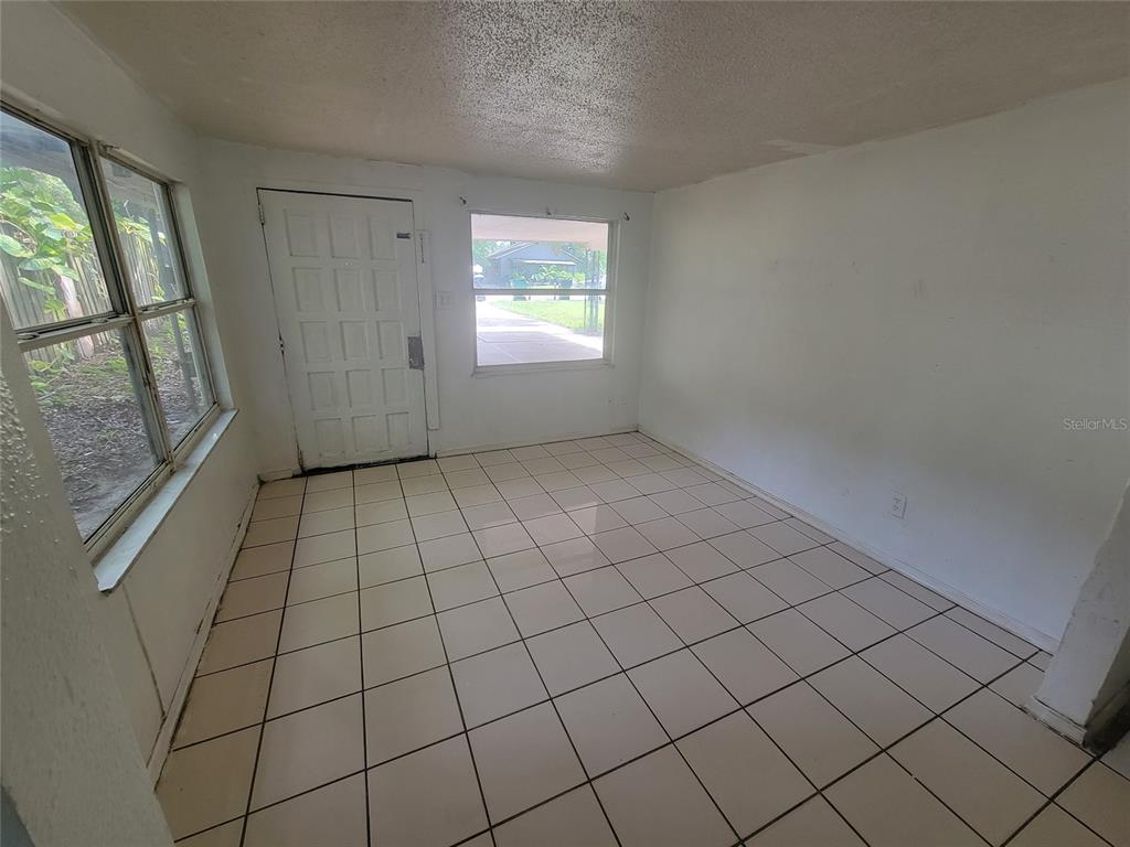 A sunroom with white tiled flooring, white walls, a front door, and multiple windows — 731 23RD STREET UNIT 3, ORLANDO, FL