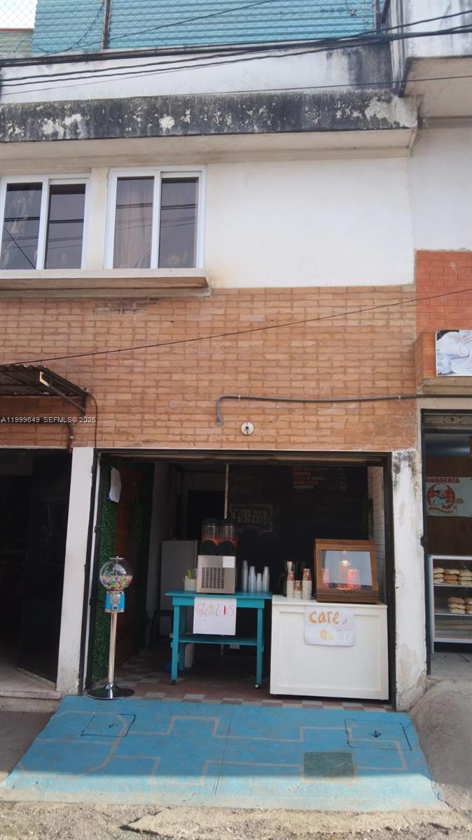 A small storefront features a brick facade, a blue table with a slushy machine, and a display case — 9 calle 8-95 zona11, MA 01057, MA