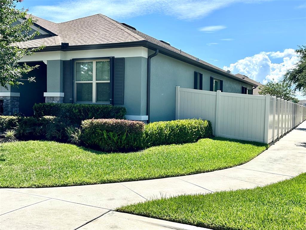 A single-story house with gray stucco siding, a white vinyl fence, and a manicured lawn — 1168 NARCOOSSEE DEL SOL, ST CLOUD, FL