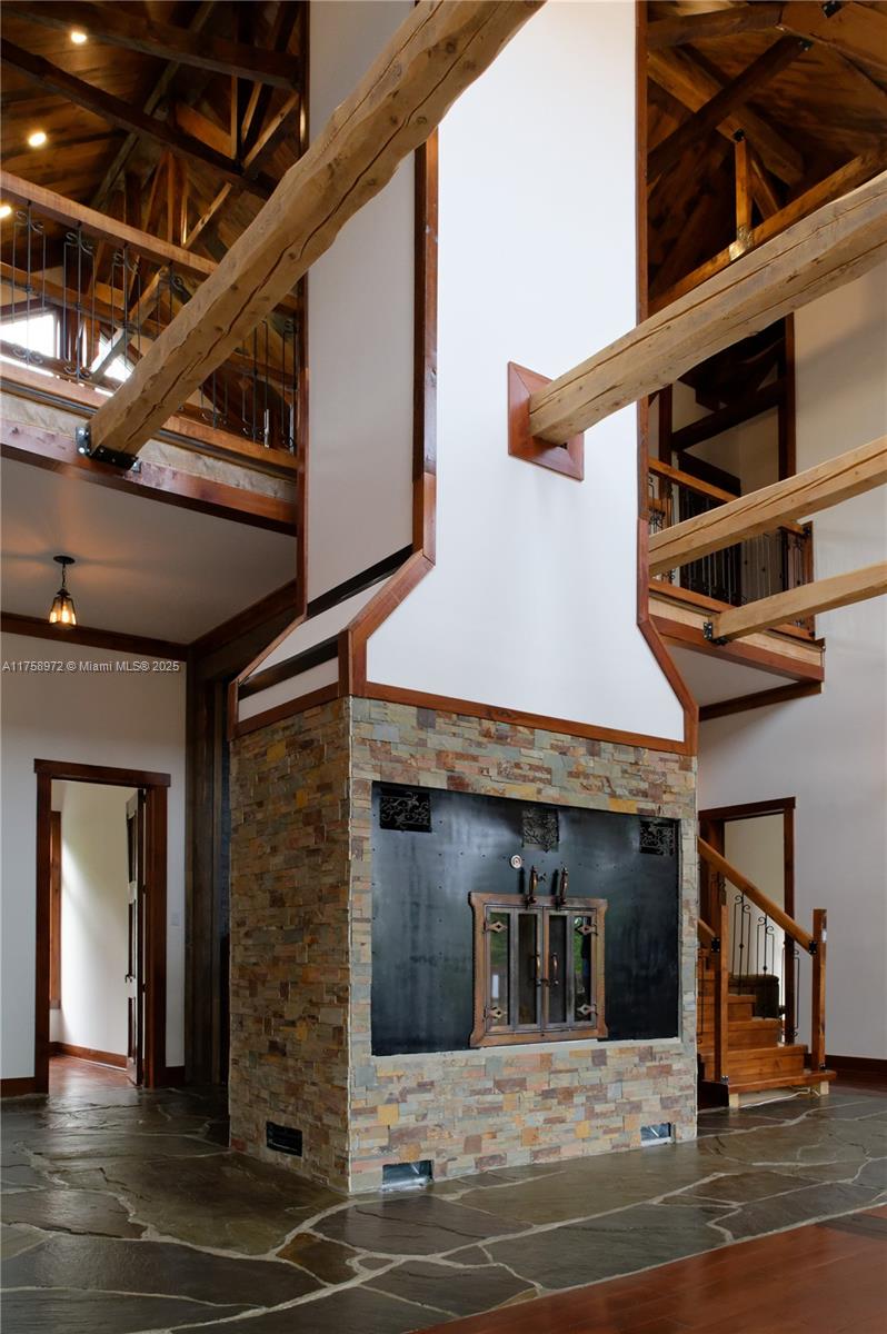 A rustic living room features a large stone fireplace, exposed wooden beams, and vaulted ceilings — 1150,10e Rang, QC J0K 1Z0, QC