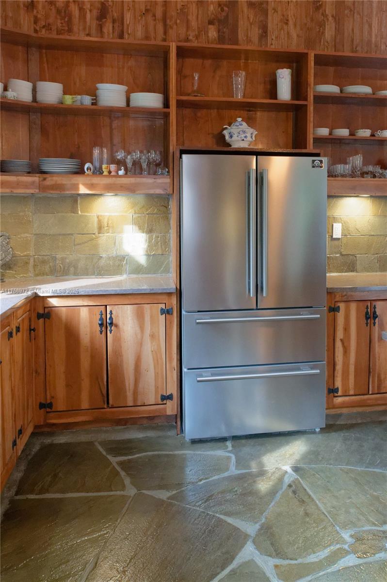 A kitchen features wooden cabinetry, open shelving, a stainless steel refrigerator, and stone flooring — 1150,10e Rang, QC J0K 1Z0, QC