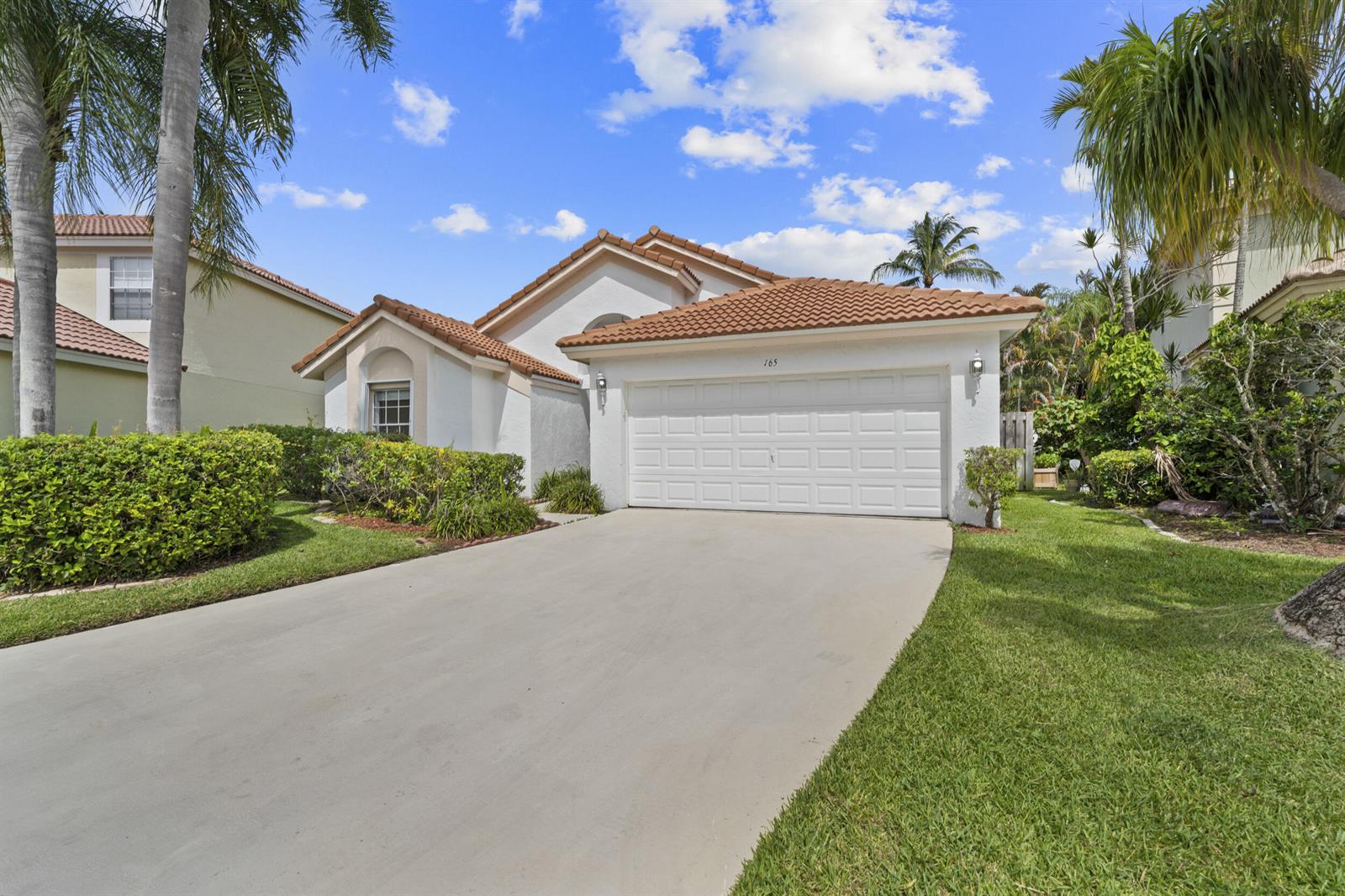 A single-story house with a white stucco facade, a tiled roof, and a concrete driveway — 165 St Michaels Court, Jupiter FL 33458, JUPITER, FL