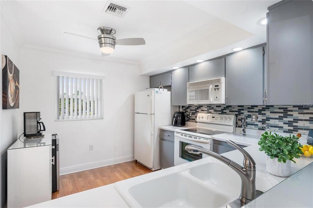 A kitchen with gray cabinets, a white refrigerator, a tiled backsplash, and a ceiling fan — 2700 NEBRASKA AVENUE UNIT 5-203, PALM HARBOR, FL