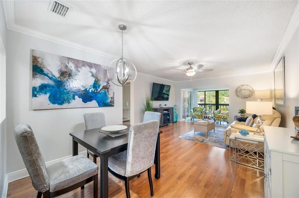 A dining area with a dark table and grey chairs opens into a living room — 2700 NEBRASKA AVENUE UNIT 5-203, PALM HARBOR, FL