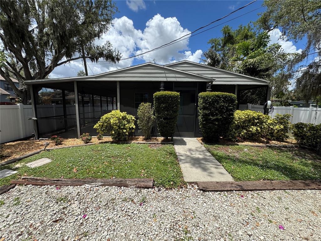 A single-story house features a screened-in front porch, a concrete walkway, and landscaped bushes — 2751 72ND AVENUE DRIVE E, SARASOTA, FL