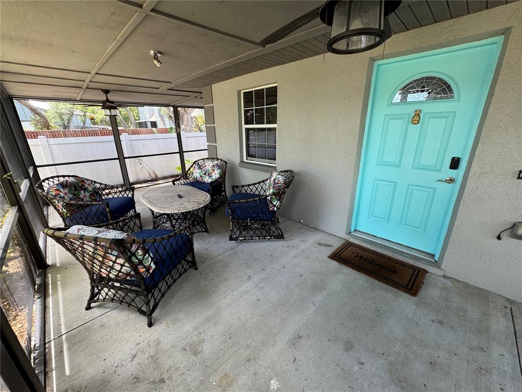 A screened-in porch features wicker furniture, a concrete floor, and a light blue front door — 2751 72ND AVENUE DRIVE E, SARASOTA, FL