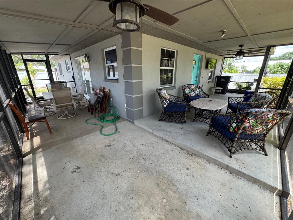A screened-in concrete patio features outdoor furniture, a ceiling fan, and a light blue door — 2751 72ND AVENUE DRIVE E, SARASOTA, FL