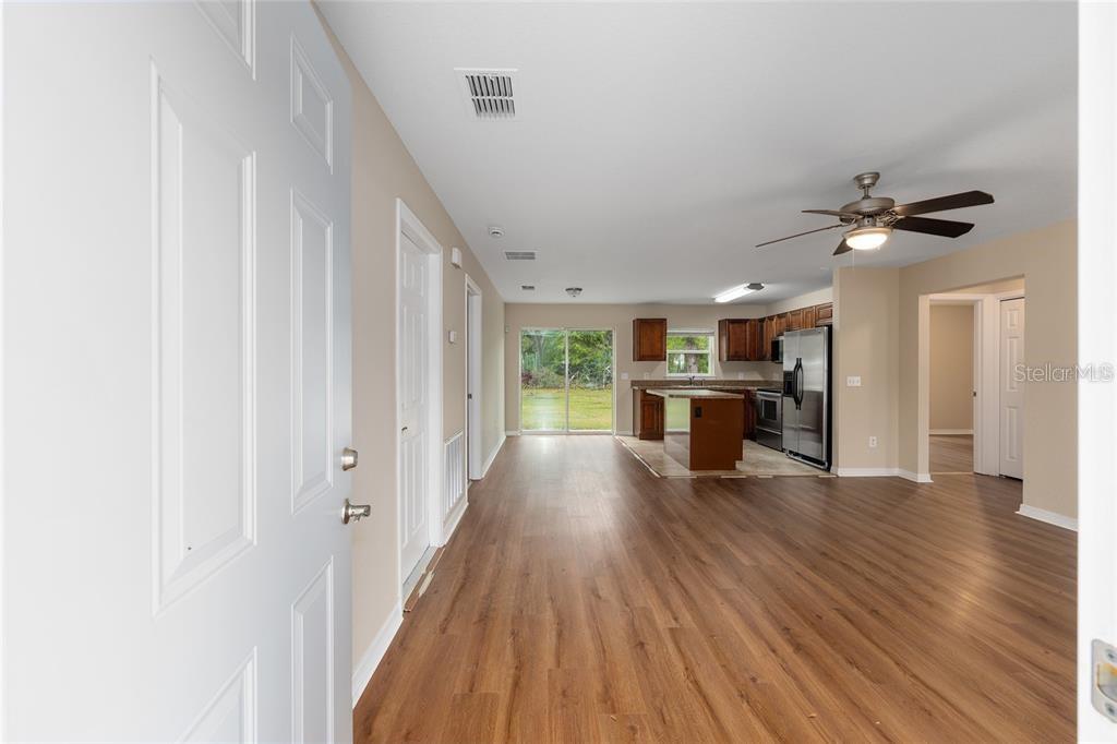 An open-concept living area with wood-look flooring leads to a kitchen with dark wood cabinets — 6975 SE 124TH LANE, BELLEVIEW, FL