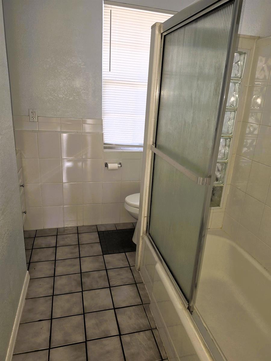 A bathroom features a tiled floor, a shower with glass doors, and a toilet — 814 Poplar Drive # B, Lake Park FL 33403, LAKE PARK, FL