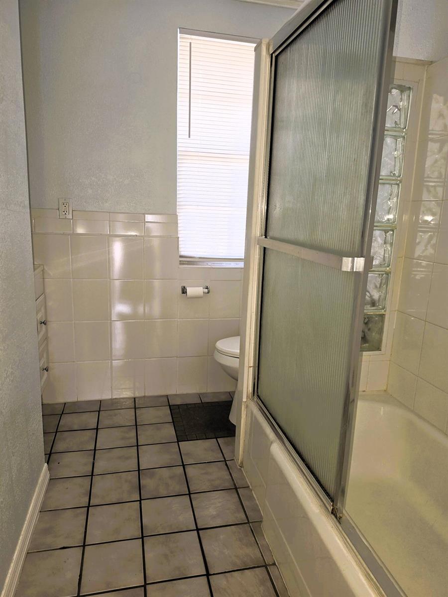A bathroom features a tiled floor, a shower with sliding glass doors, and a toilet — 814 Poplar Drive # B, Lake Park FL 33403, LAKE PARK, FL