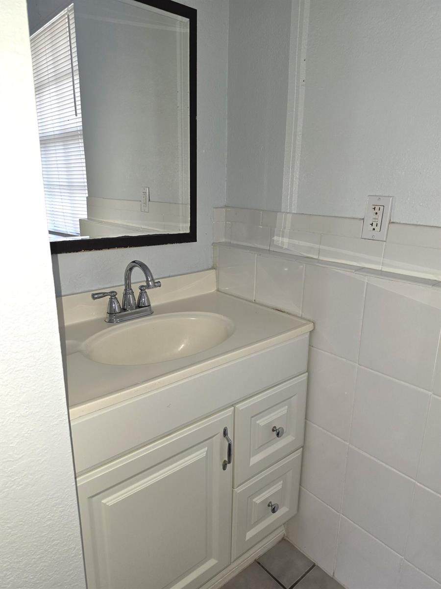 A bathroom vanity features a white cabinet, a chrome faucet, and a wall-mounted mirror — 814 Poplar Drive # B, Lake Park FL 33403, LAKE PARK, FL