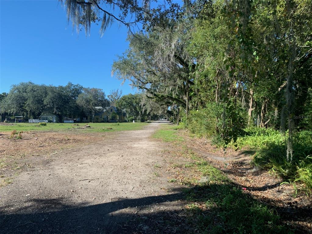 A dirt path leads through a wooded lot toward houses in the distance — S VERNON AVENUE, KISSIMMEE, FL