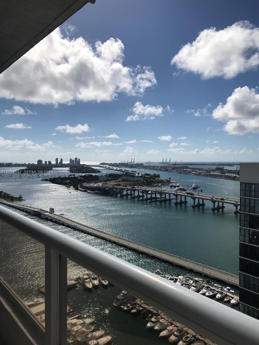 A high-angle view from a balcony overlooks a marina, bridges, and a distant city skyline — 1717 N Bayshore Dr # 3646, Miami FL 33132, MIAMI, FL