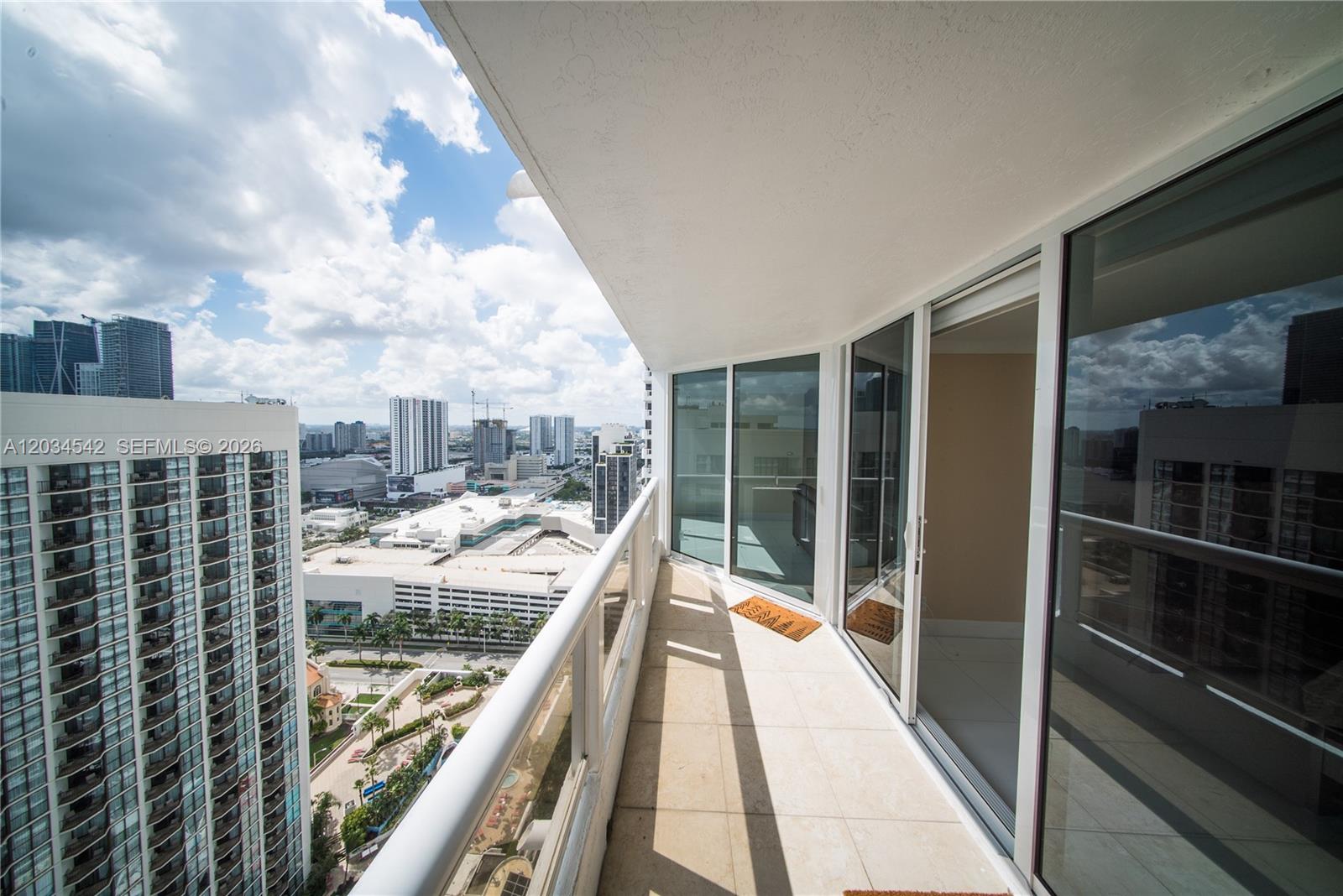 A high-rise balcony with tile flooring overlooks a city skyline and neighboring apartment buildings — 1717 N Bayshore Dr # 3646, Miami FL 33132, MIAMI, FL