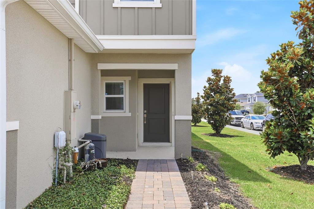 A paved walkway leads to the dark front door of a tan two-story suburban home — 2274 CARRABELLE WAY, SANFORD, FL