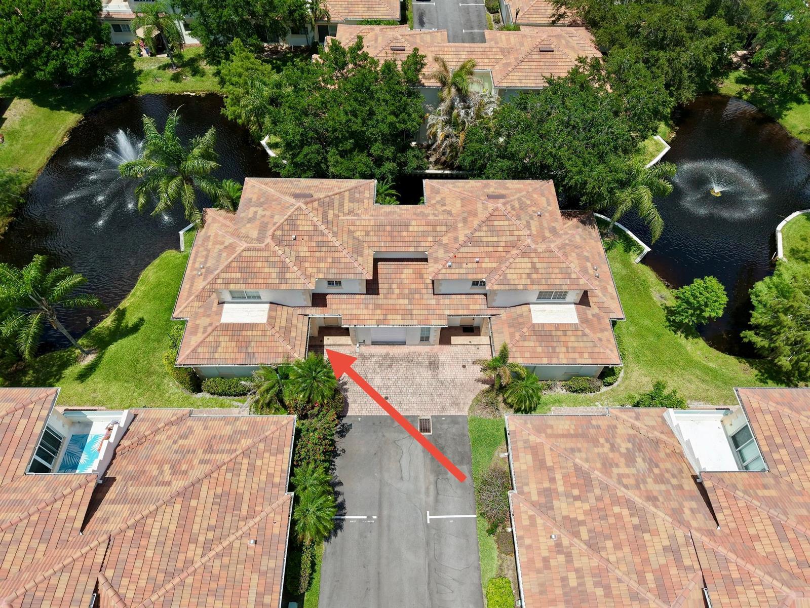 An aerial view of a multi-unit residential building with a tiled roof and ponds — 568 7th Square, Vero Beach FL 32962, VERO BEACH, FL