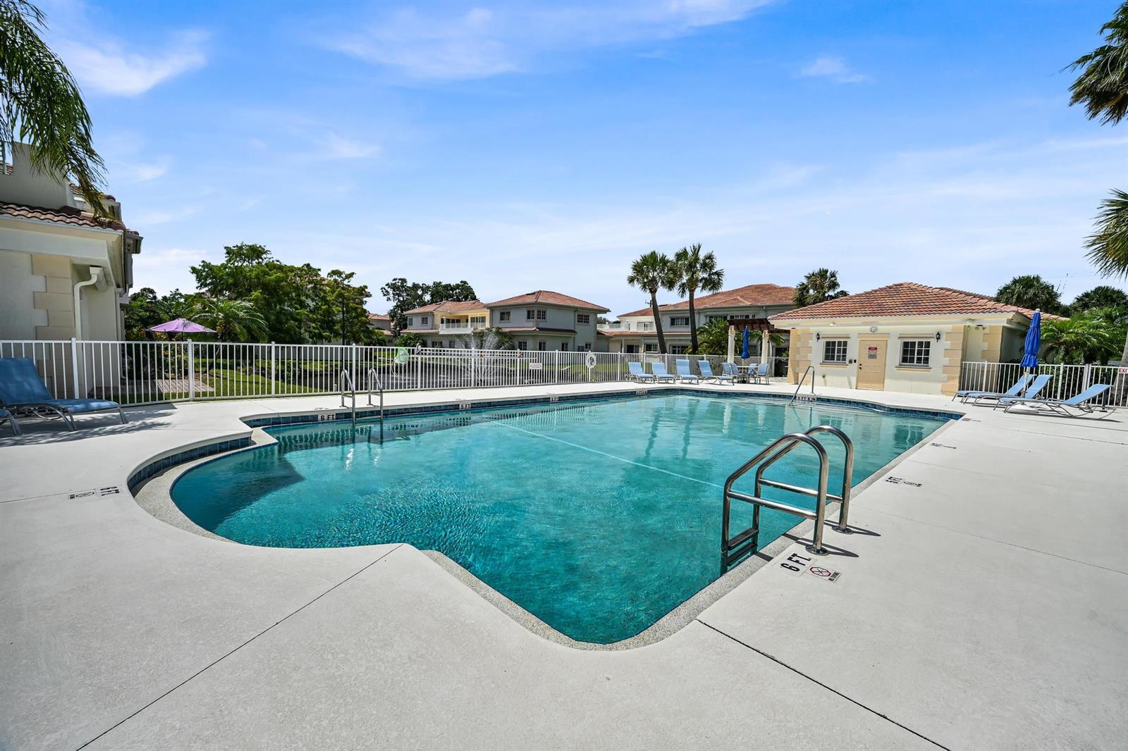 A rectangular swimming pool with a metal ladder sits on a concrete deck near buildings — 568 7th Square, Vero Beach FL 32962, VERO BEACH, FL