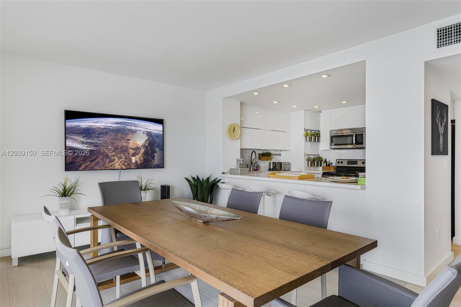 A dining area with a wooden table and chairs sits adjacent to an open kitchen — 11111 Biscayne Blvd # 8C, Miami FL 33181, MIAMI, FL