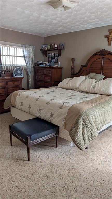 A bedroom features a wooden bed frame, a dresser, a footstool, and terrazzo flooring — 1619 PEARCE ROAD NW, WINTER HAVEN, FL