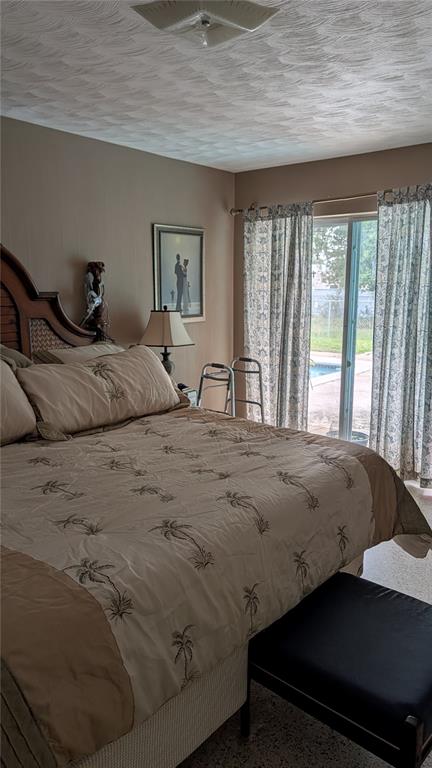 A bedroom features a palm-print bedspread, a bedside lamp, and sliding glass doors to a pool — 1619 PEARCE ROAD NW, WINTER HAVEN, FL