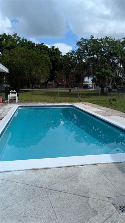 A rectangular swimming pool sits in a backyard with a concrete deck and chain-link fence — 1619 PEARCE ROAD NW, WINTER HAVEN, FL
