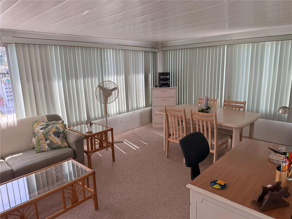A sunroom features a sofa, dining set, desk, and vertical blinds covering the windows — 315 PEACE MANOR, PALMETTO, FL