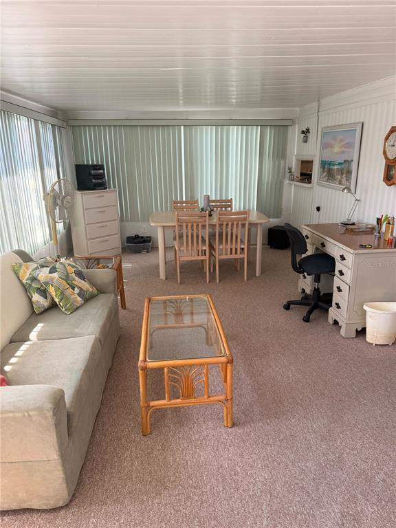 A sunroom features a sofa, dining set, desk, and carpeted flooring under a paneled ceiling — 315 PEACE MANOR, PALMETTO, FL