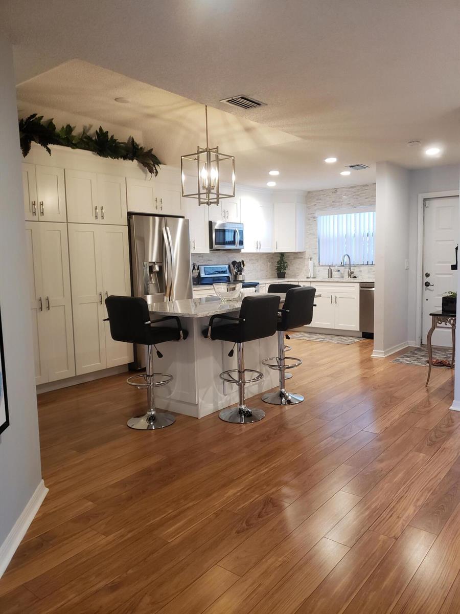 A kitchen with white cabinets, stainless steel appliances, a center island, and wood-look flooring — 6021 SE Landing Way Bldg 2 Unit #2 Bldg 2, Stuart FL 34997, STUART, FL