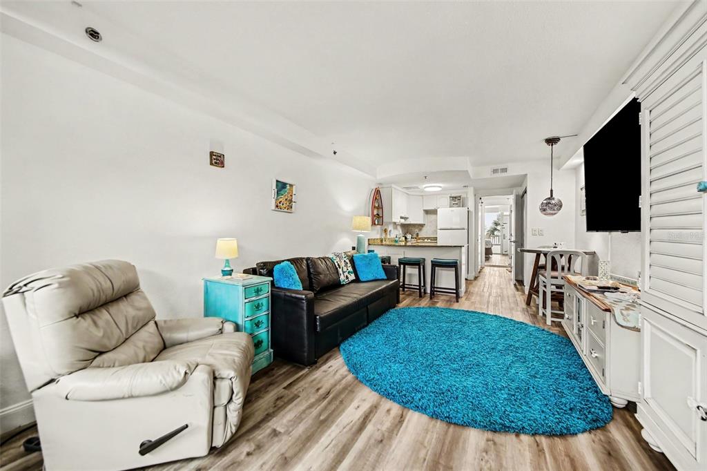 A living room features a white recliner, a black sofa, and a bright blue rug — 2700 N ATLANTIC AVENUE UNIT 214, DAYTONA BEACH, FL