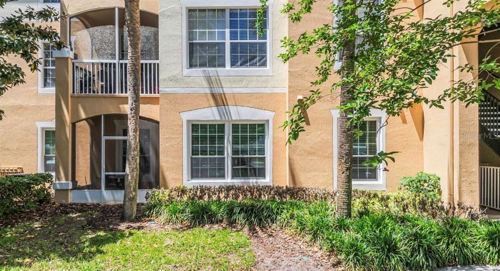 The exterior of a multi-story apartment building features tan stucco walls and screened-in balconies — 3190 DANTE DRIVE UNIT 109, ORLANDO, FL