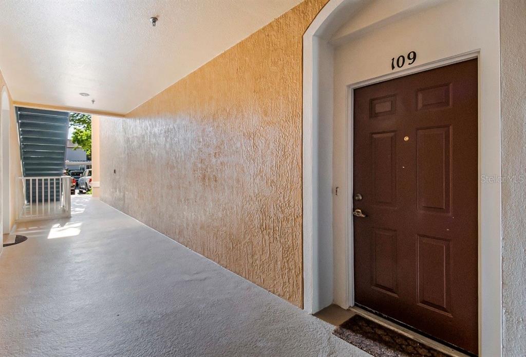 A brown apartment door labeled 109 sits at the end of a covered outdoor walkway — 3190 DANTE DRIVE UNIT 109, ORLANDO, FL
