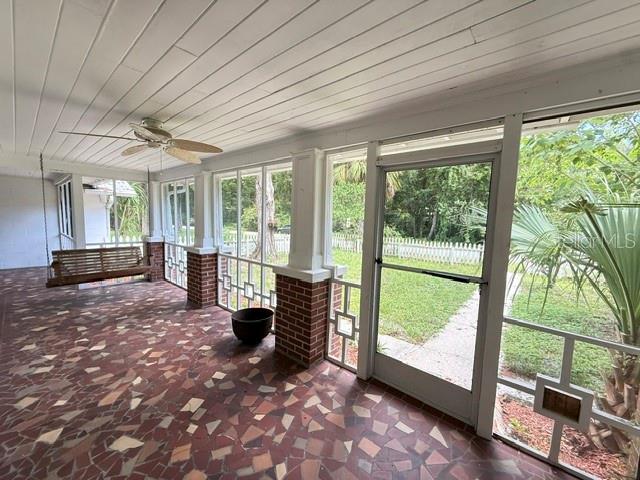 A screened-in porch features a mosaic tile floor, a ceiling fan, and a hanging wooden swing — 331 SW 3RD STREET, BRONSON, FL