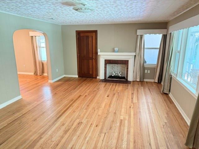 A living room with hardwood floors, a fireplace, and an arched doorway to another room — 331 SW 3RD STREET, BRONSON, FL