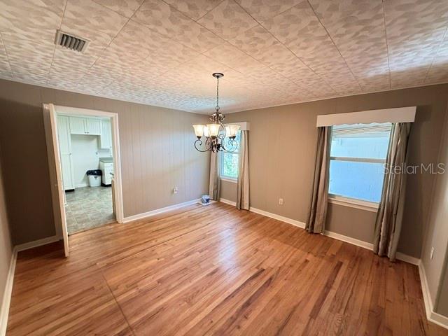 A dining room with wood flooring, a chandelier, and a doorway leading to a kitchen — 331 SW 3RD STREET, BRONSON, FL