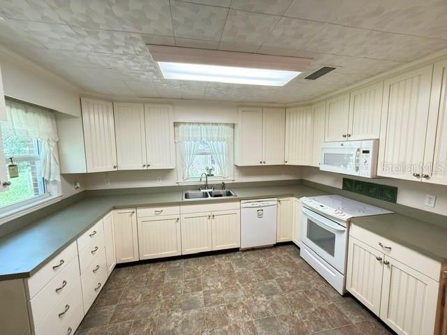 A kitchen features white cabinetry, green countertops, a white stove, and a tiled ceiling — 331 SW 3RD STREET, BRONSON, FL