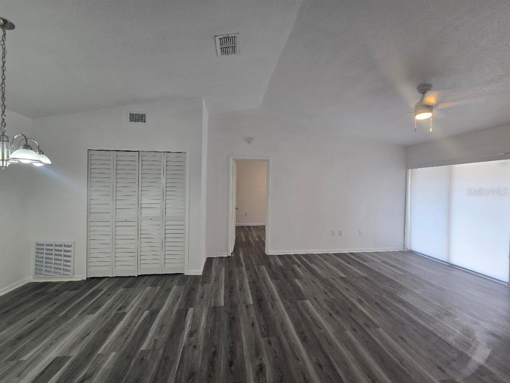 A living room features gray wood-look flooring, white walls, a ceiling fan, and louvered closet doors — 5232 VIA HACIENDA CIRCLE UNIT A217, ORLANDO, FL