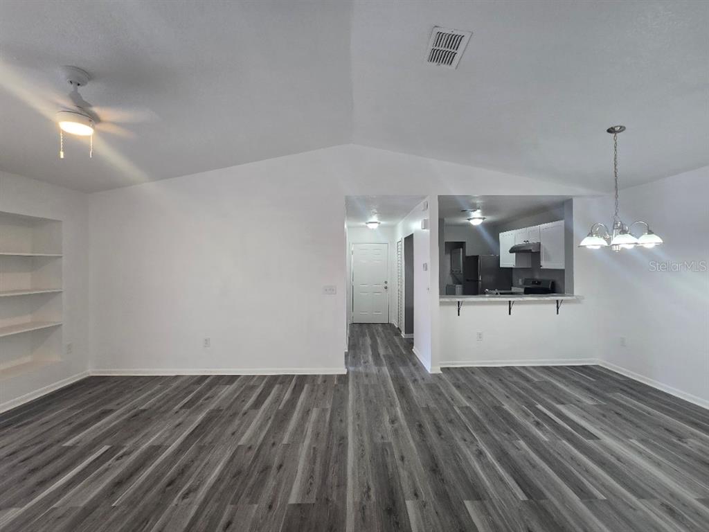 A living area features gray wood-look flooring, white walls, built-in shelves, and a kitchen pass-through — 5232 VIA HACIENDA CIRCLE UNIT A217, ORLANDO, FL